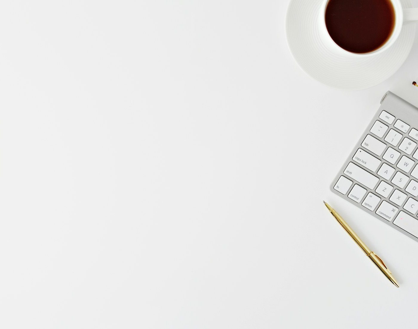 Keyboard, notebook and coffee on a white desk