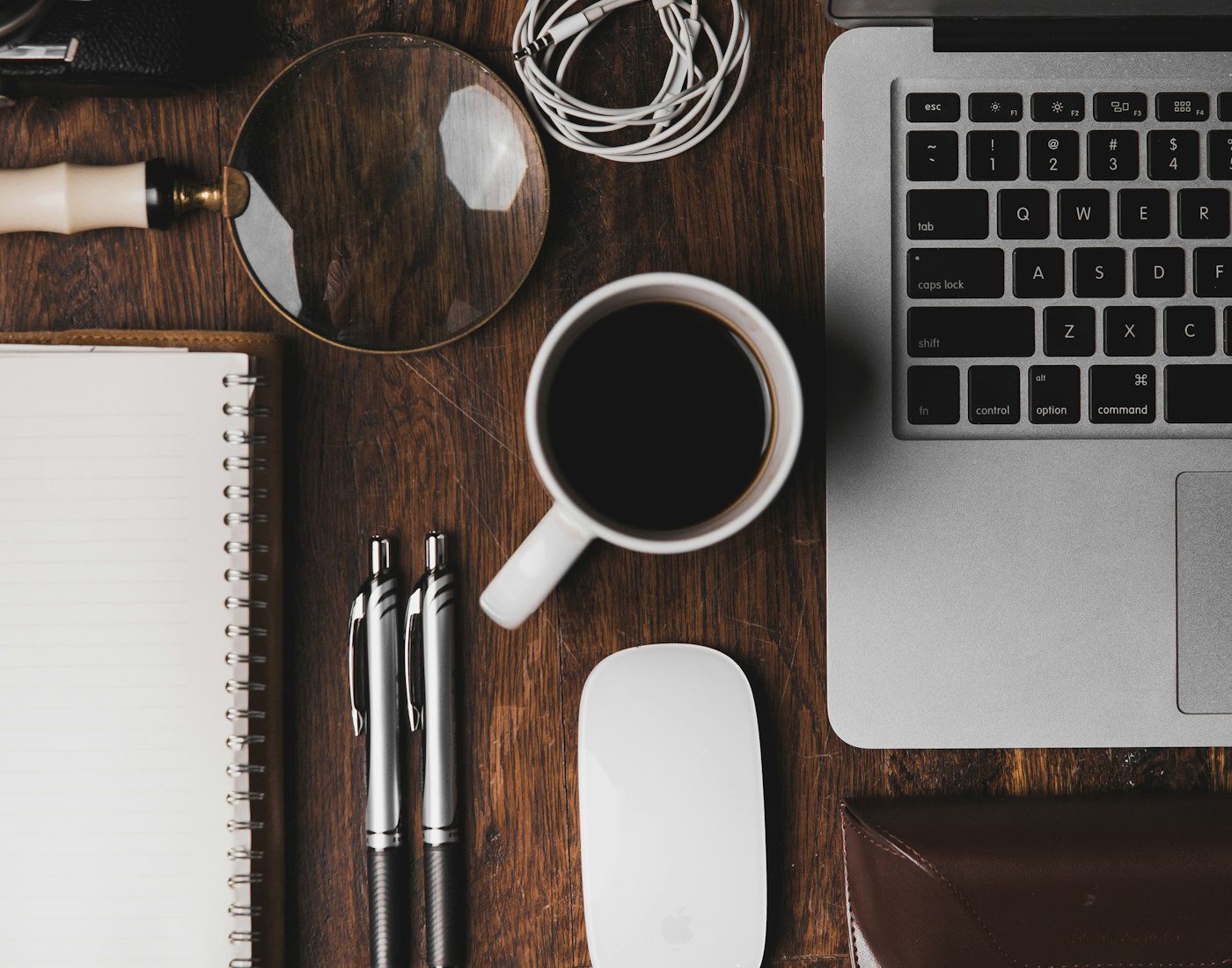 Notebook, pens, coffee and laptop seen from above