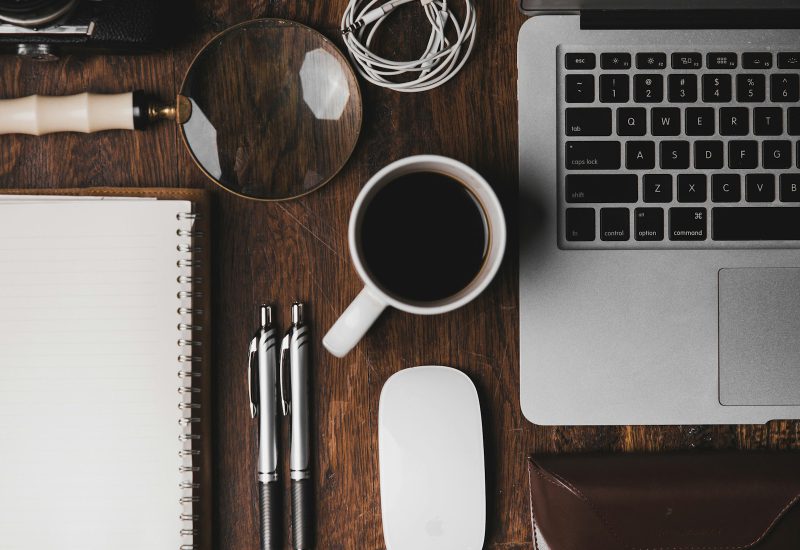 Notebook, pens, coffee and laptop seen from above