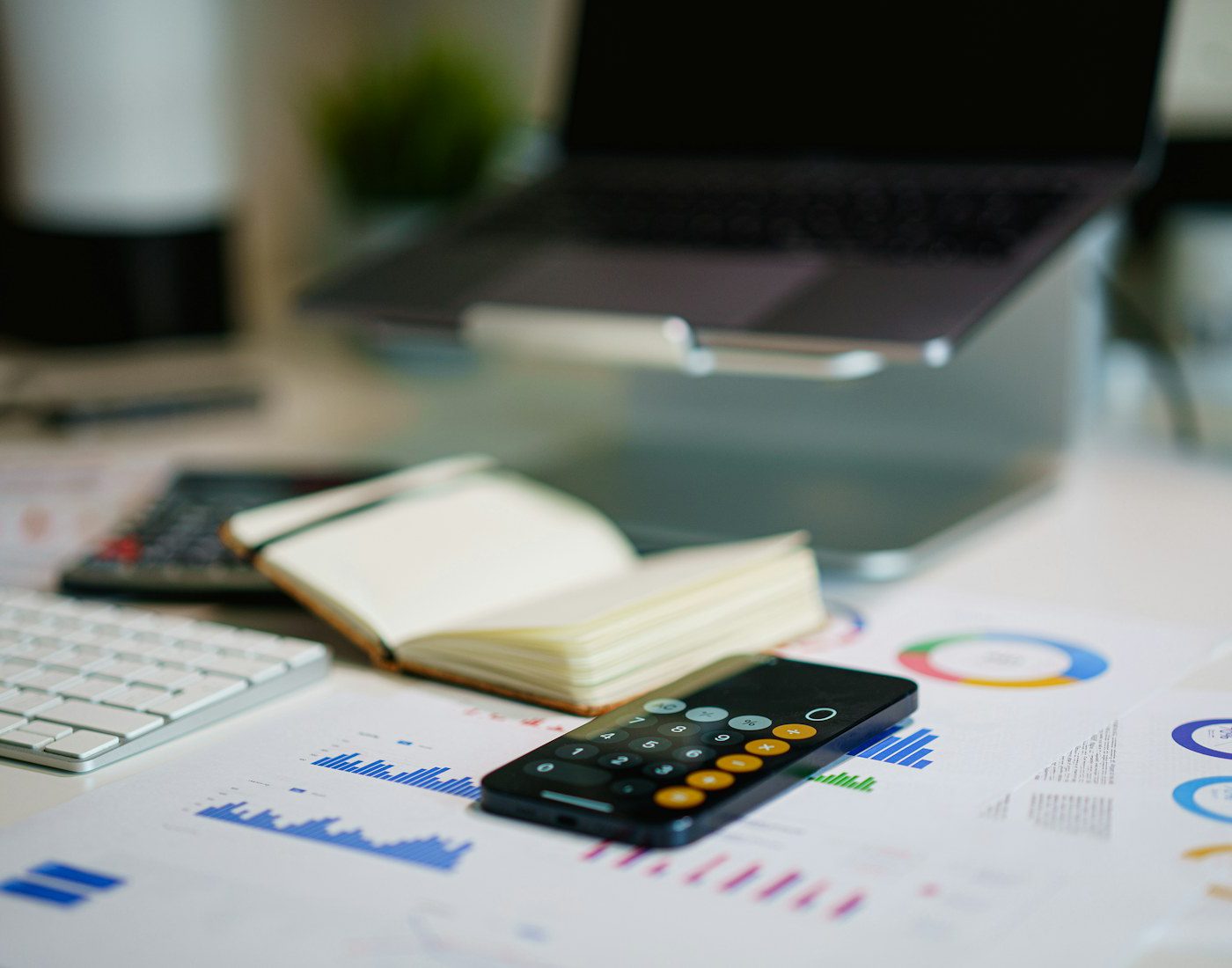 Calculator, notebook and printed charts on an office desk