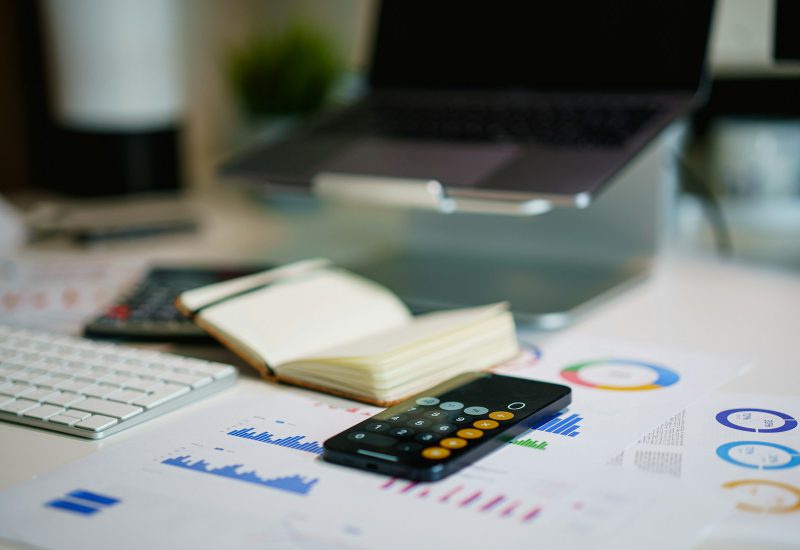 Calculator, notebook and printed charts on an office desk