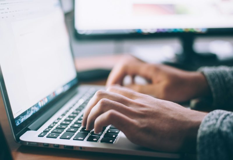 Hands typing on a laptop keyboard