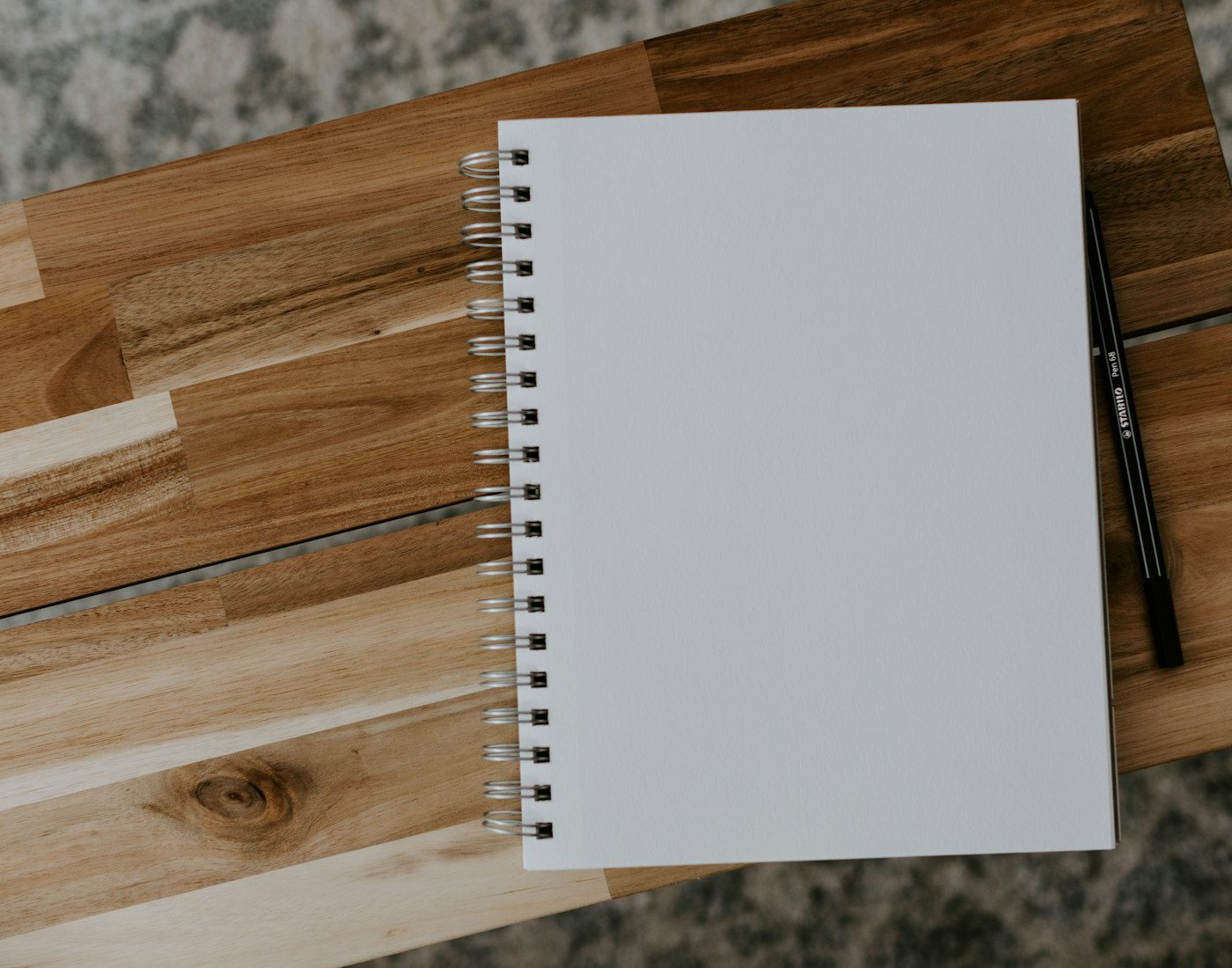 Blank spiral notebook and pen on a wooden table