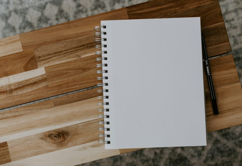 Blank spiral notebook and pen on a wooden table