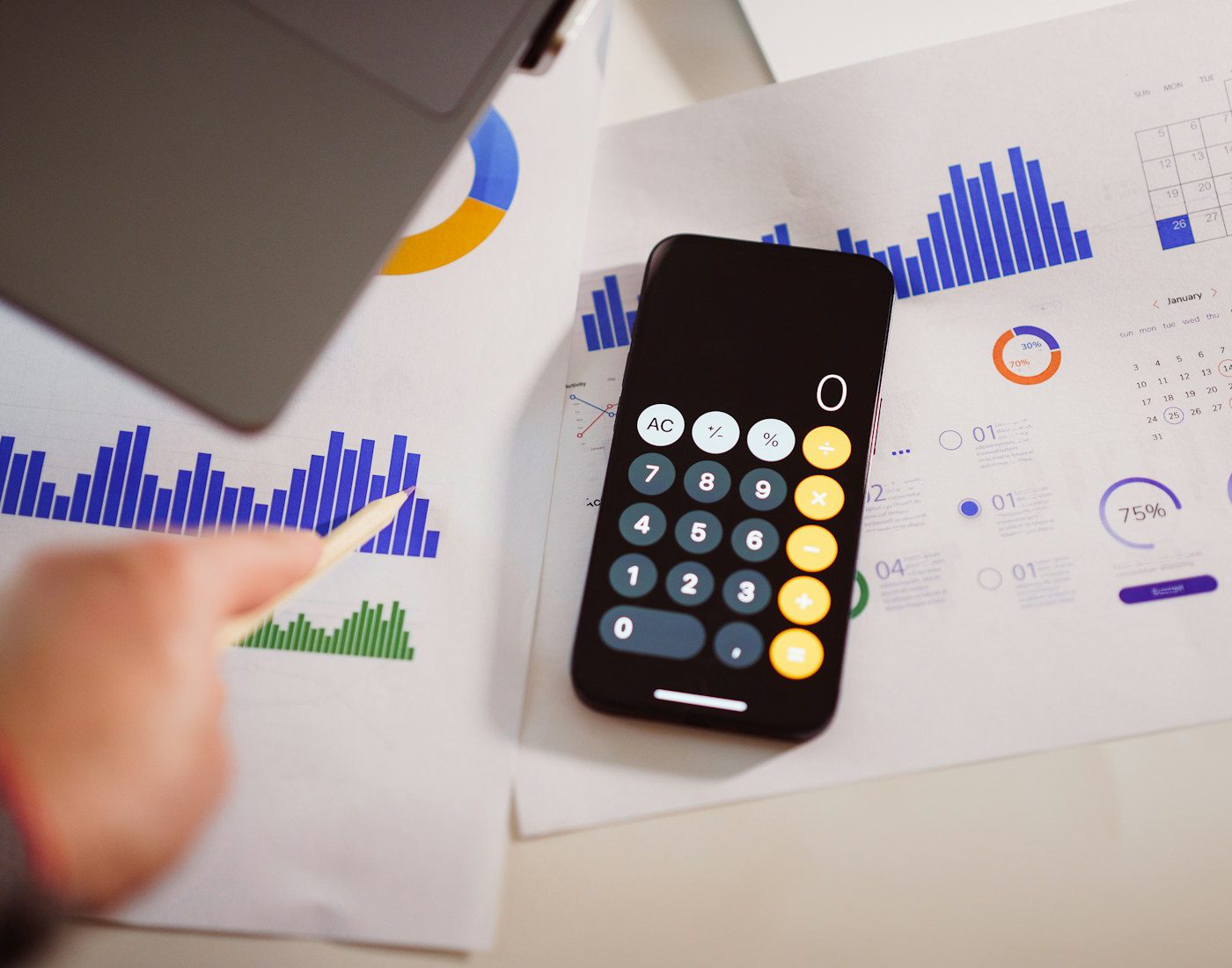 Calculator app on a phone beside printed financial charts