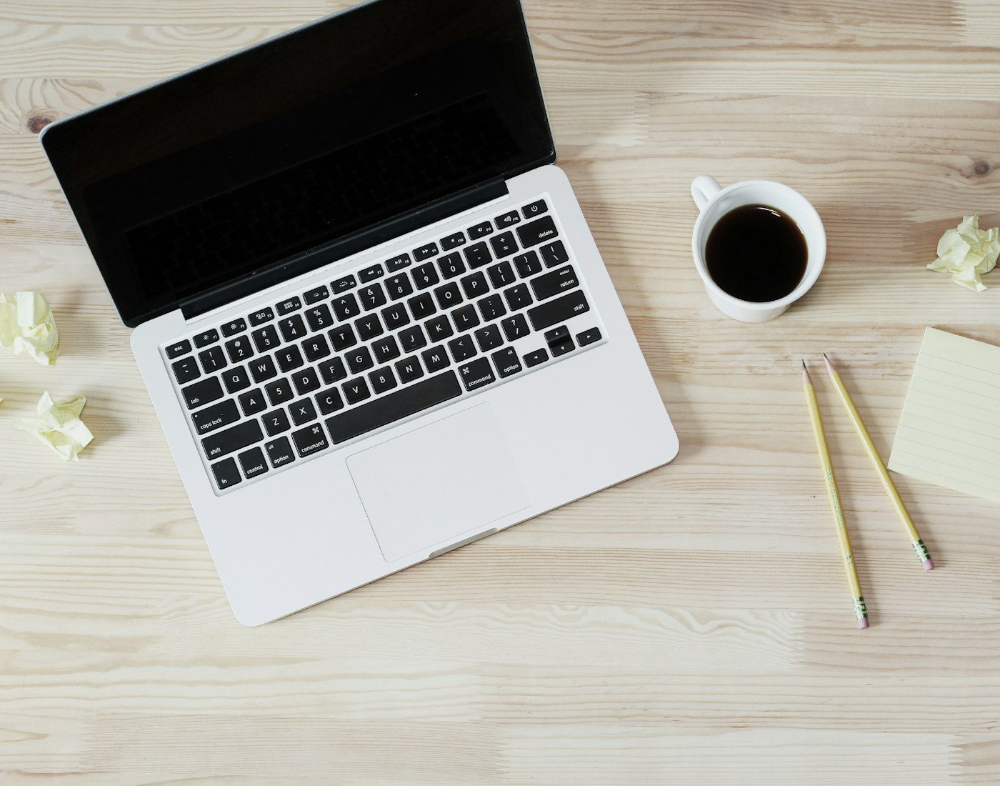 Laptop, coffee and stationery arranged on a wooden desk