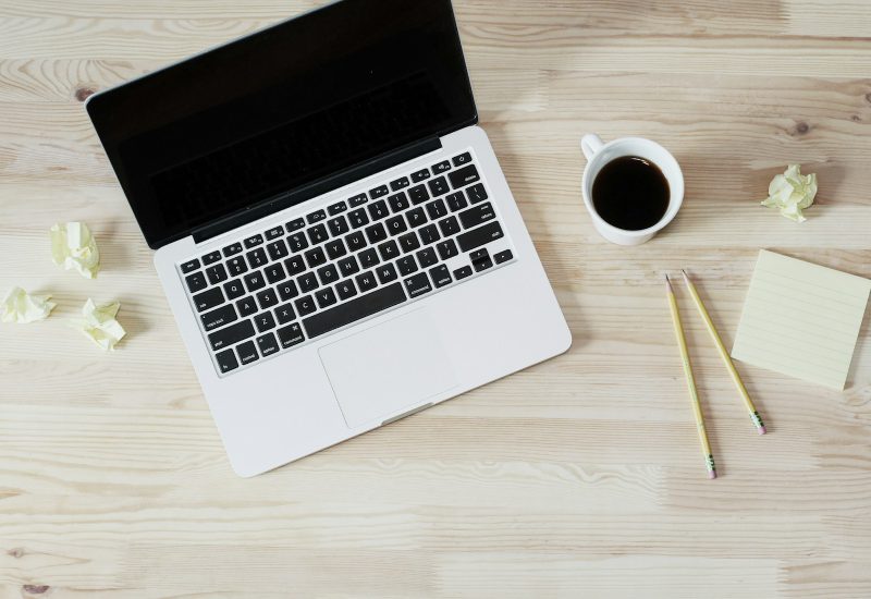 Laptop, coffee and stationery arranged on a wooden desk
