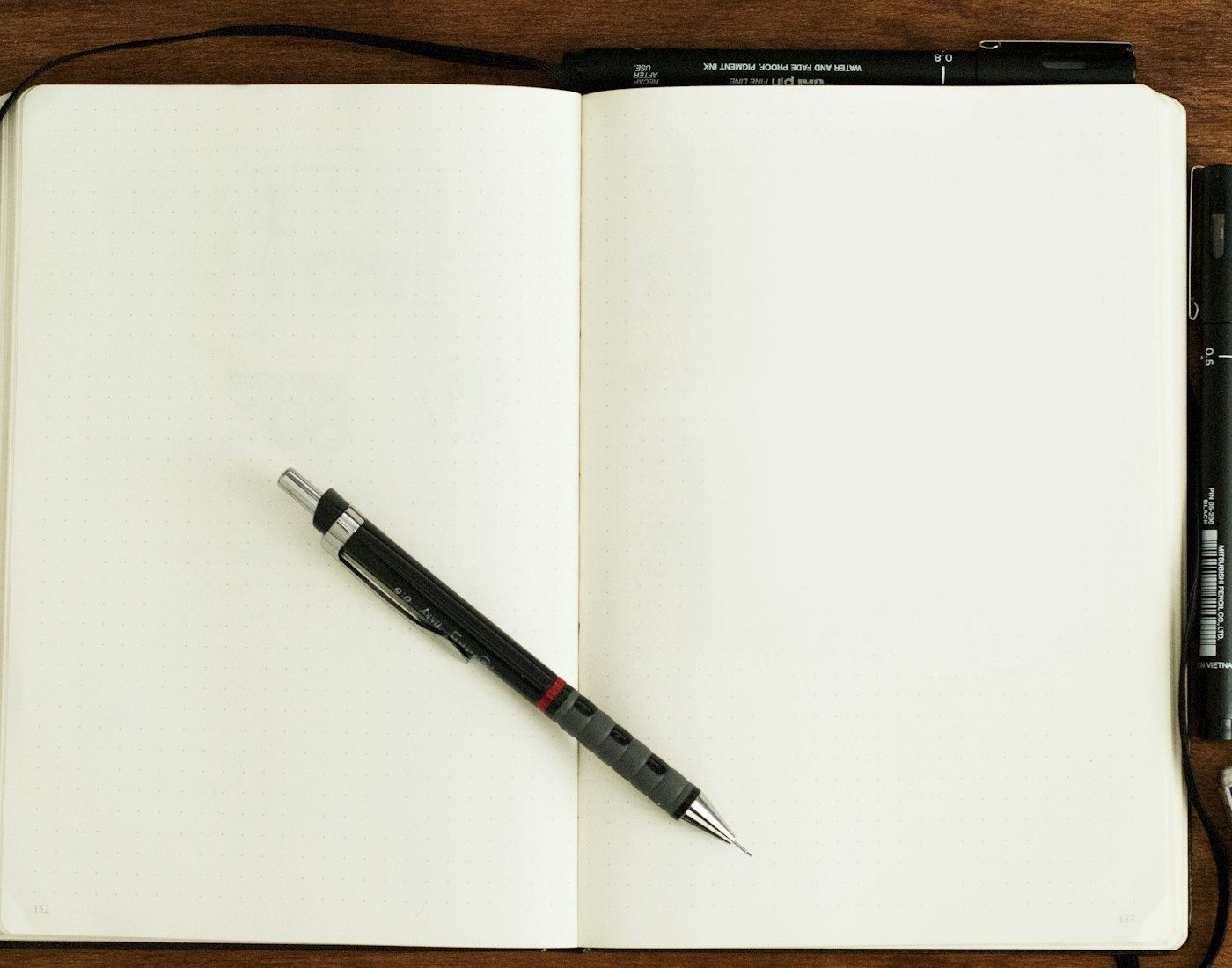 Blank notebook with a pen resting across the pages