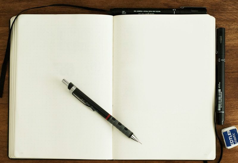 Blank notebook with a pen resting across the pages