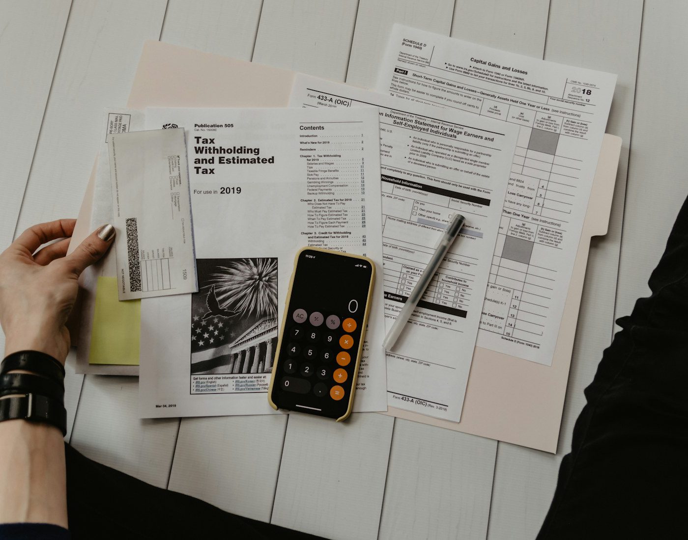 Hands reviewing paperwork beside a phone calculator