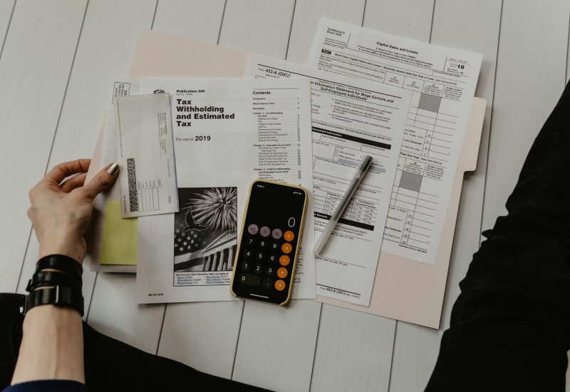 Hands reviewing paperwork beside a phone calculator