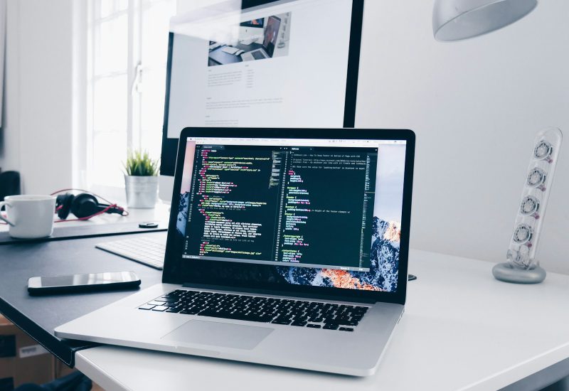Laptop displaying code in a bright workspace