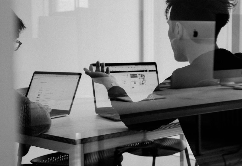 Colleagues reviewing work on a laptop at a desk